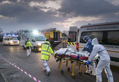 Emergency medical personnel carries a patient affected with coronavirus from a military hospital to an ambulance. Photo: AFP